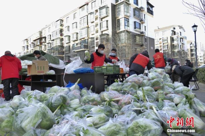资料图：社区工作者在生活物资保障点为居民分装蔬菜。中新社记者 佟郁 摄
