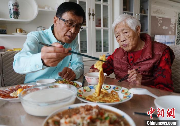 图为台商陈志明(左一)和母亲品尝台湾美食菜脯蛋。　马铭言 摄